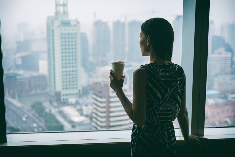 Businesswoman,Drinking,Coffee,At,Work,Contemplative,Looking,Out,The,Window